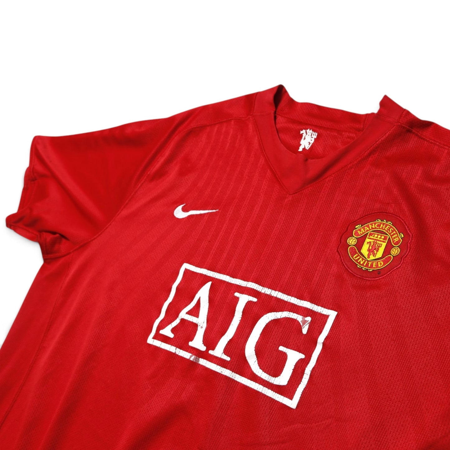 Close-up of Manchester United crest, Nike logo and AIG sponsor with visible wear