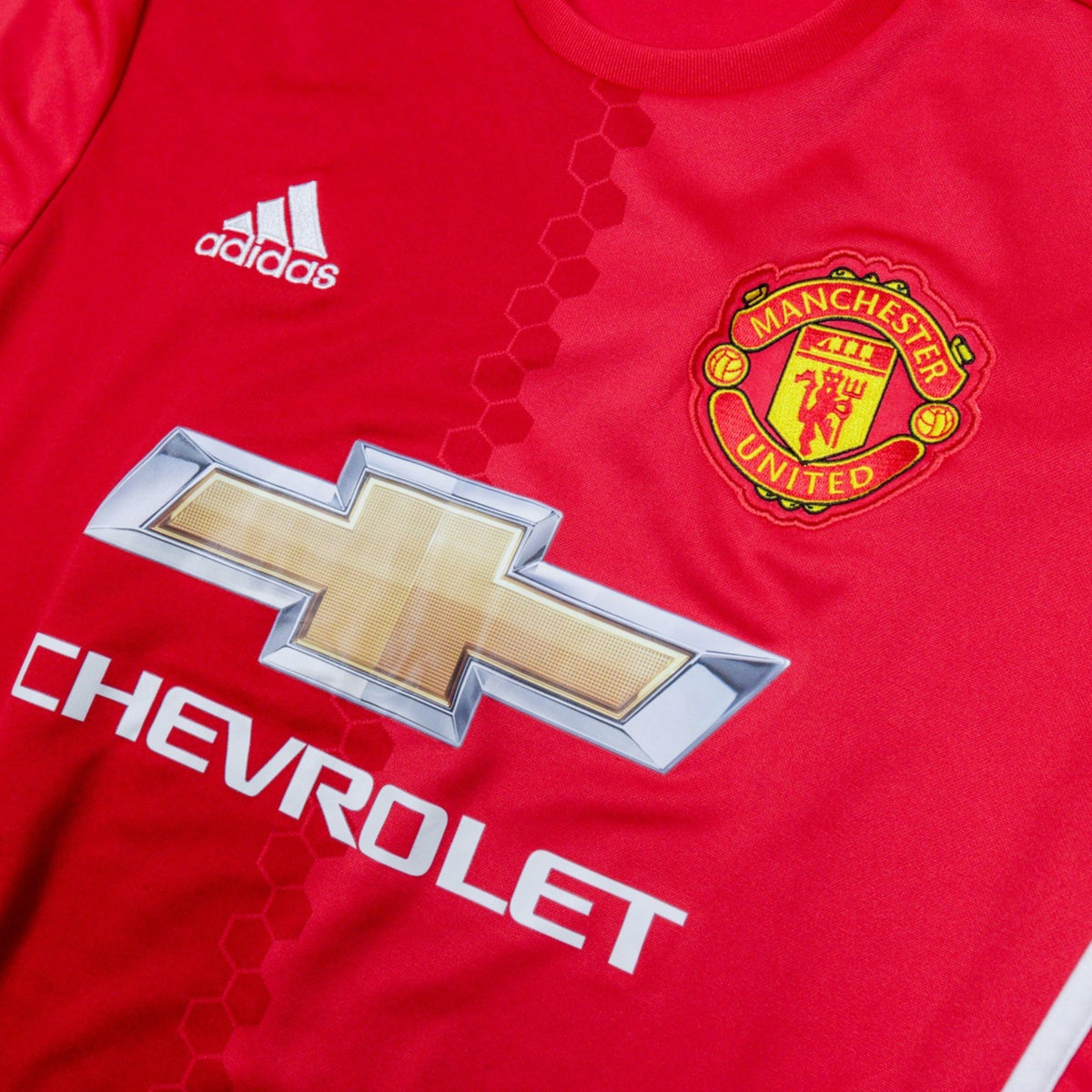 Close-up of adidas logo and Manchester United crest on the chest