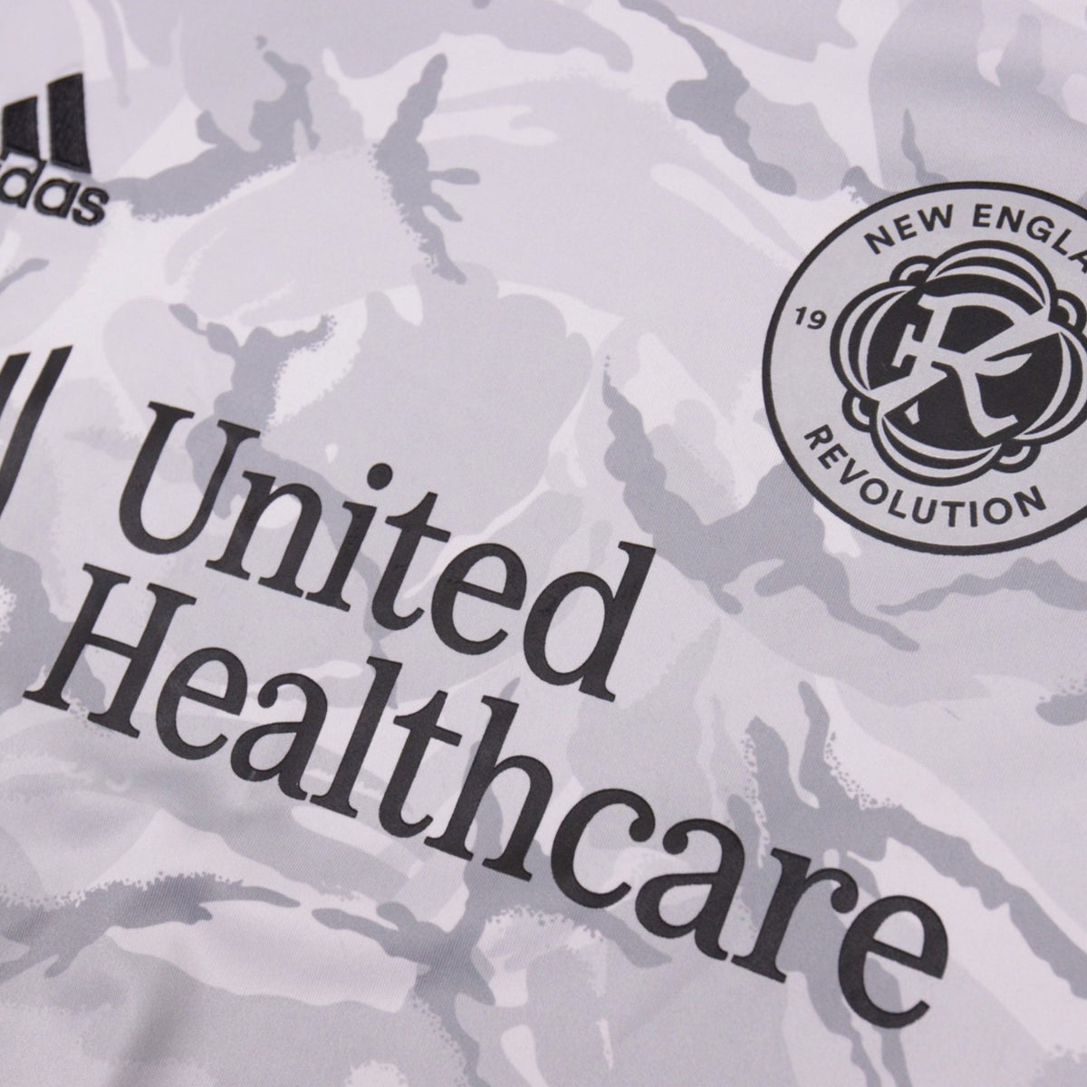 Close-up of New England Revolution crest, adidas logo and United Healthcare sponsor on the away shirt