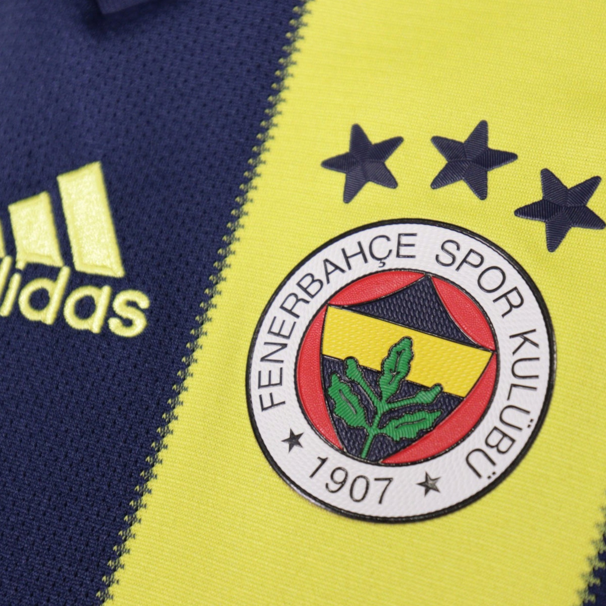 Close-up of Fenerbahçe crest with three stars and adidas logo on the shirt