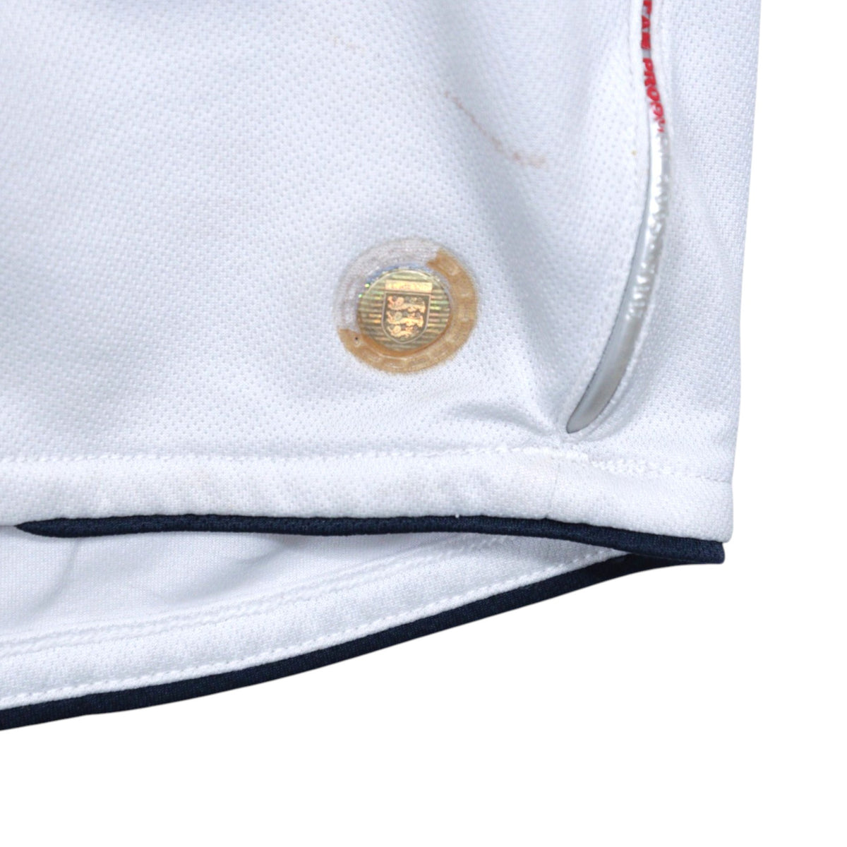 Close-up of the hem showing a gold hologram tag and a faint mark