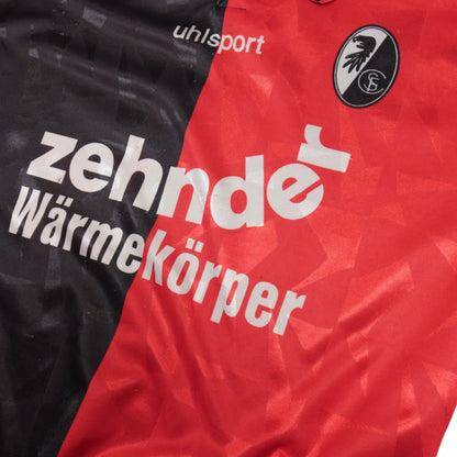 Close-up of the uhlsport logo, Zehnder Wärmekörper sponsor and SC Freiburg crest on the chest.