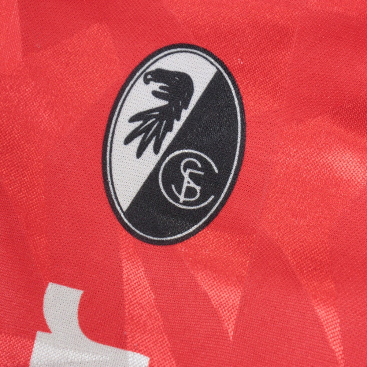 Close-up of the SC Freiburg eagle crest on the shirt's chest.