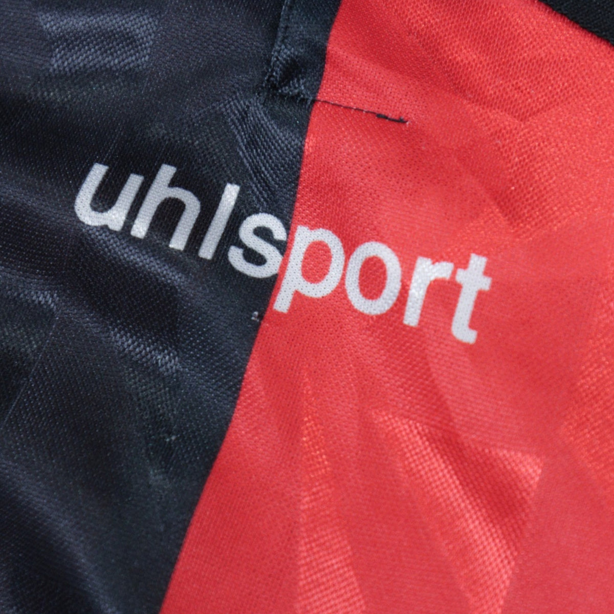 Close-up of the uhlsport logo printed near the shirt's placket.